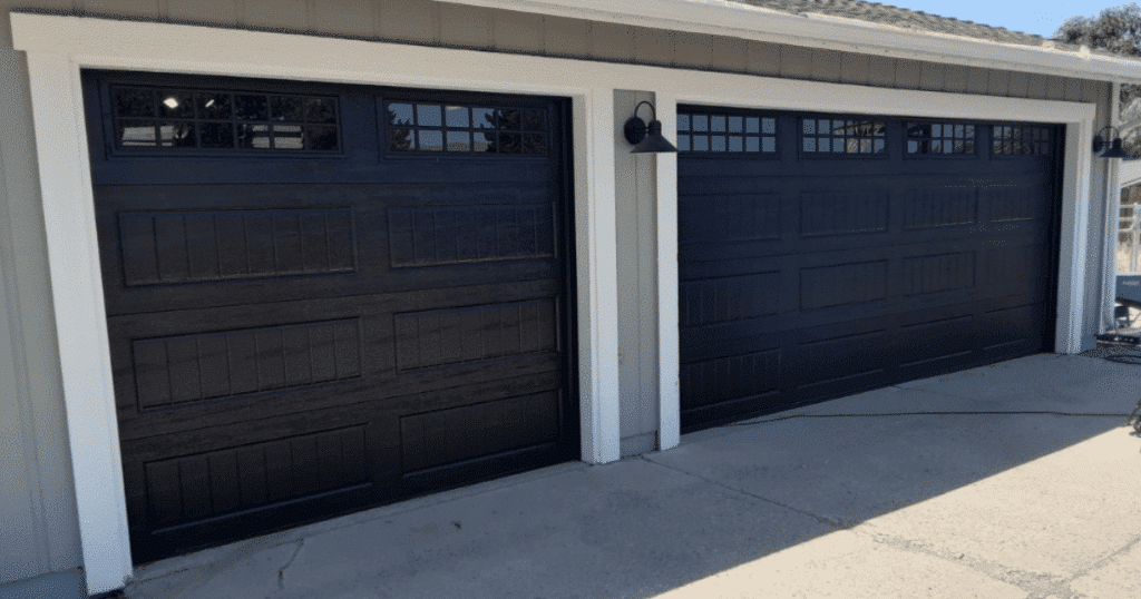 Two black garage doors with window panels.