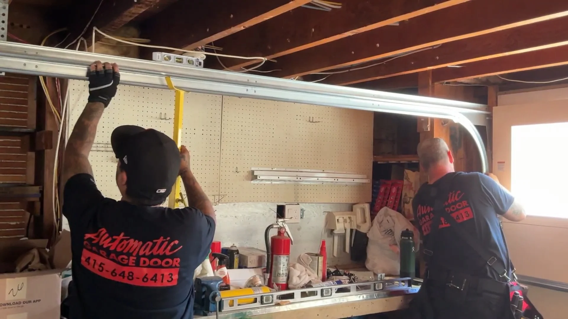 Two technicians aligning and installing an overhead track, representing a Garage Door Repair Company in San Francisco, CA.