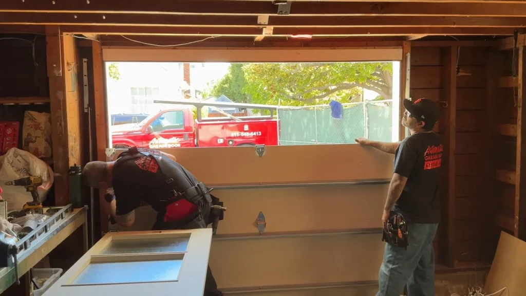 Two technicians assembling a sectional door inside a garage during Local Garage Door Repair in San Francisco.