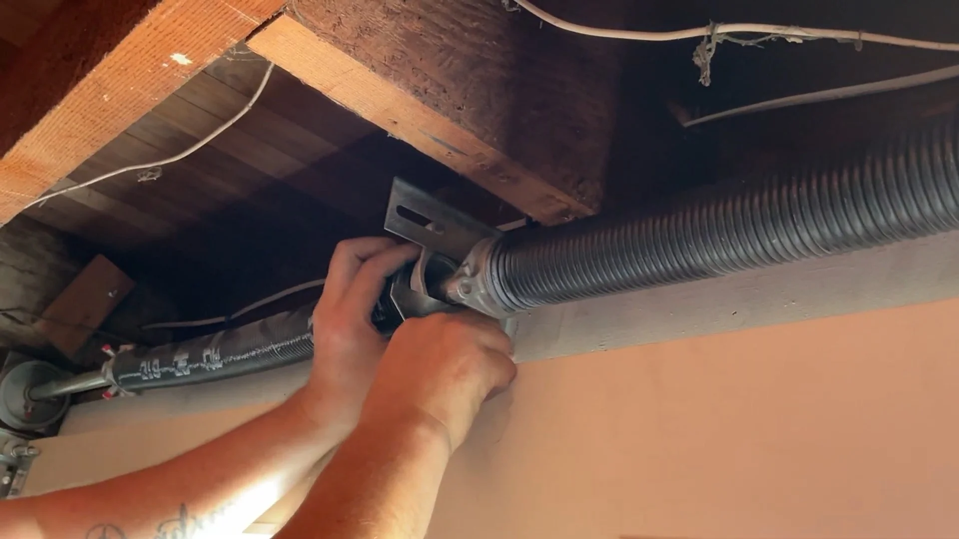 Stay Ahead of a Broken Garage Door Spring A close-up view of hands installing and securing an overhead torsion coil to perform a garage door spring replacement in San Francisco, CA.