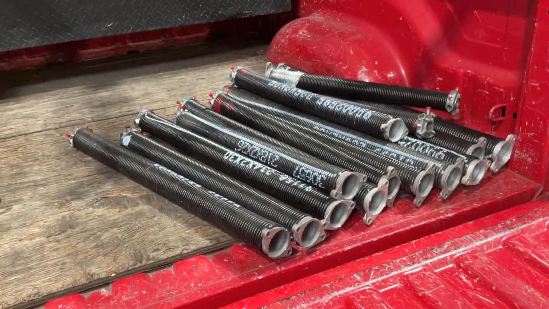 Multiple heavy-duty torsion coils lying in a truck bed, ready to be used for a garage door spring replacement.